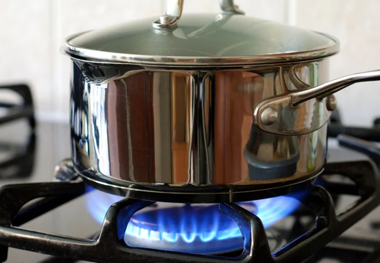 A gas cooktop next to a glass splashback