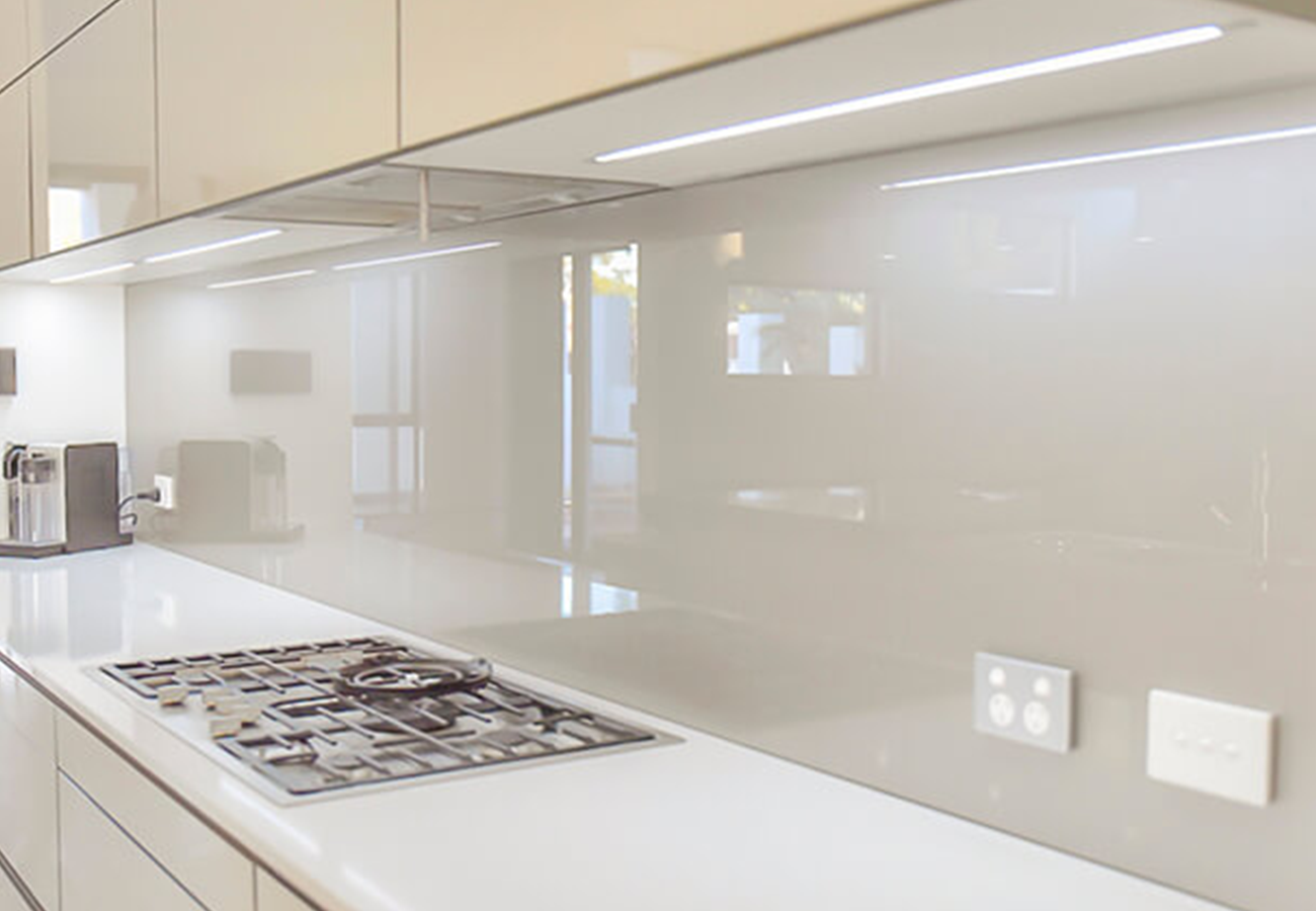 A kitchen with a vibrant coloured glass splashback